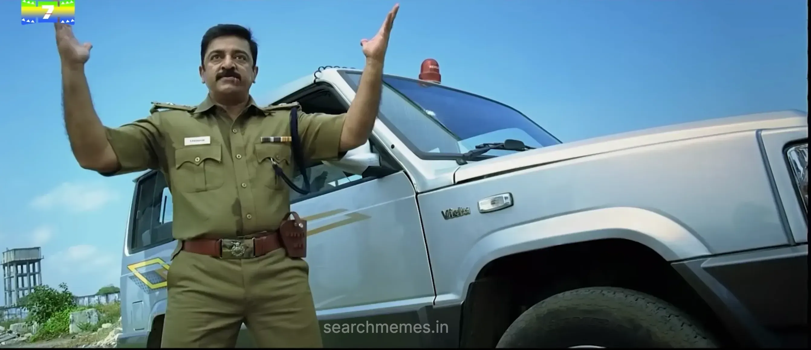 Kamal Haasan as Raghavan in a powerful pose with raised hands next to a police vehicle