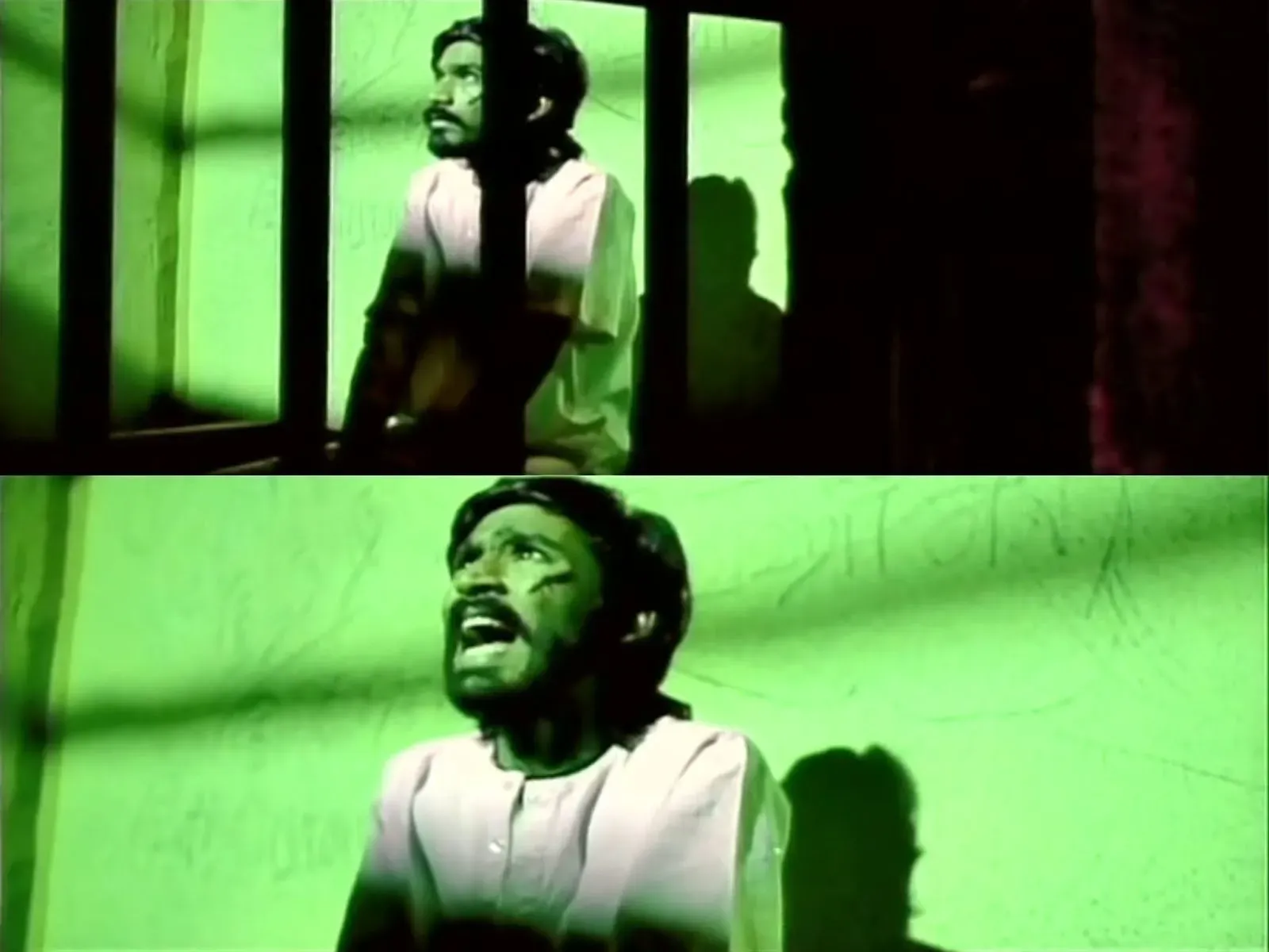 Dhanush looking around anxiously in a dimly lit prison cell