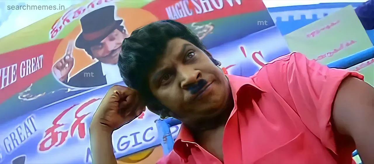 Vadivelu in a pink shirt resting his chin in his hand with a pensive look