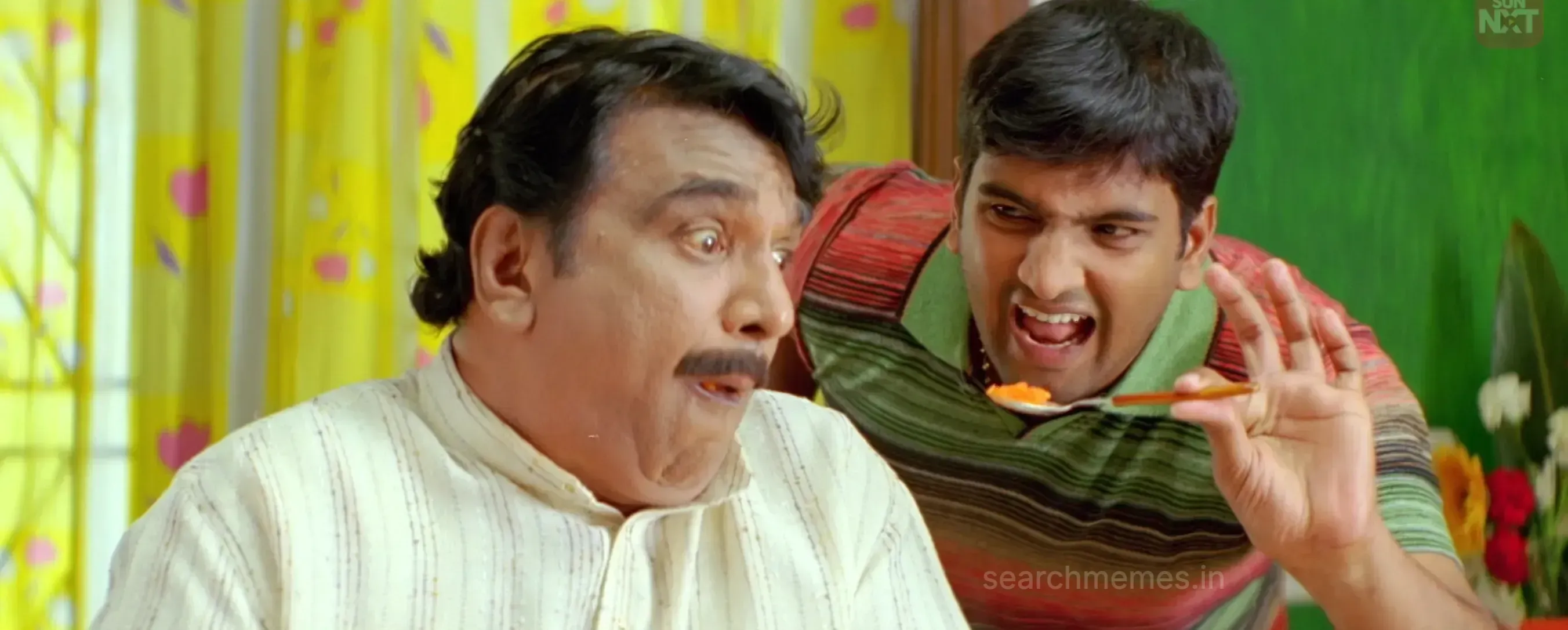A younger man feeding sweet on a spoon to an older man whose eyes pop open in panic