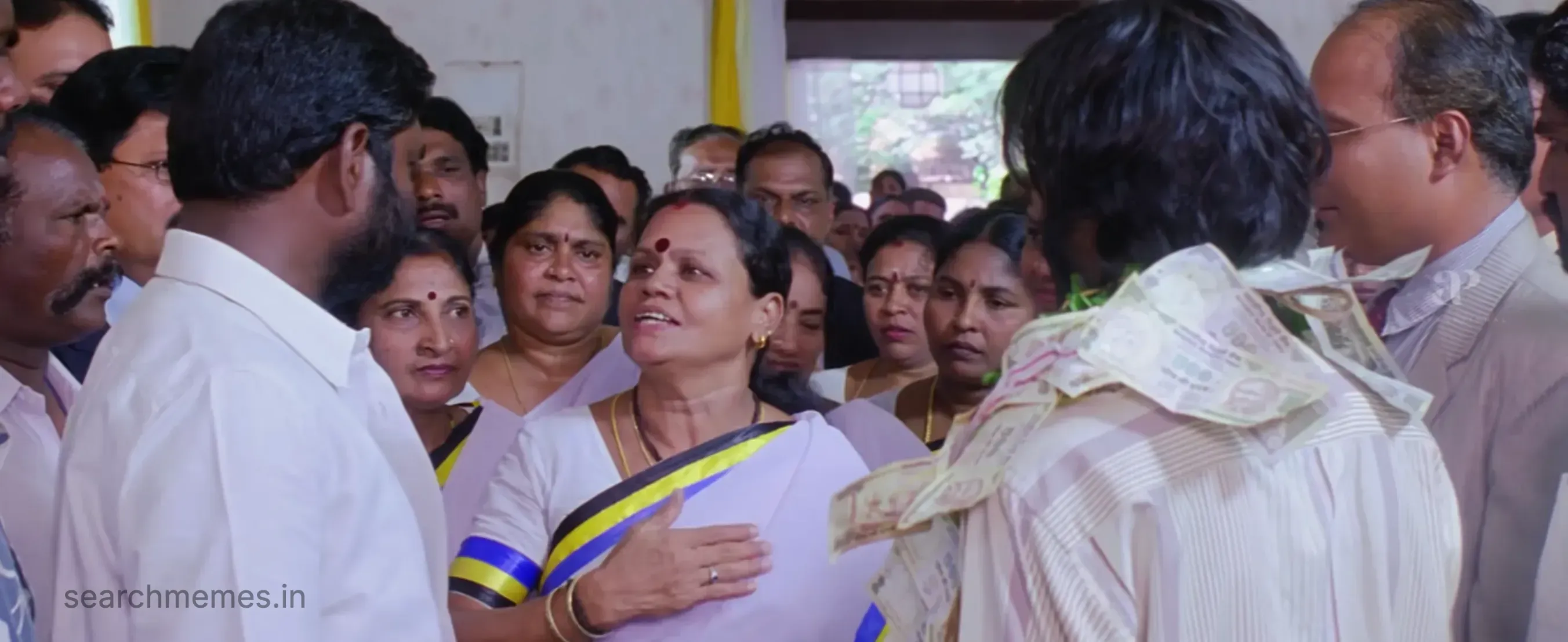 A woman smiling amidst a crowd, looking towards someone off-screen in Pudhupettai.