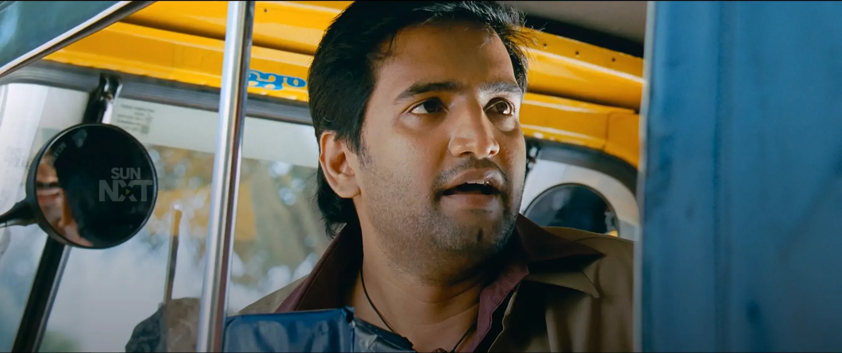 Karthi looking curiously out of an auto rickshaw cabin
