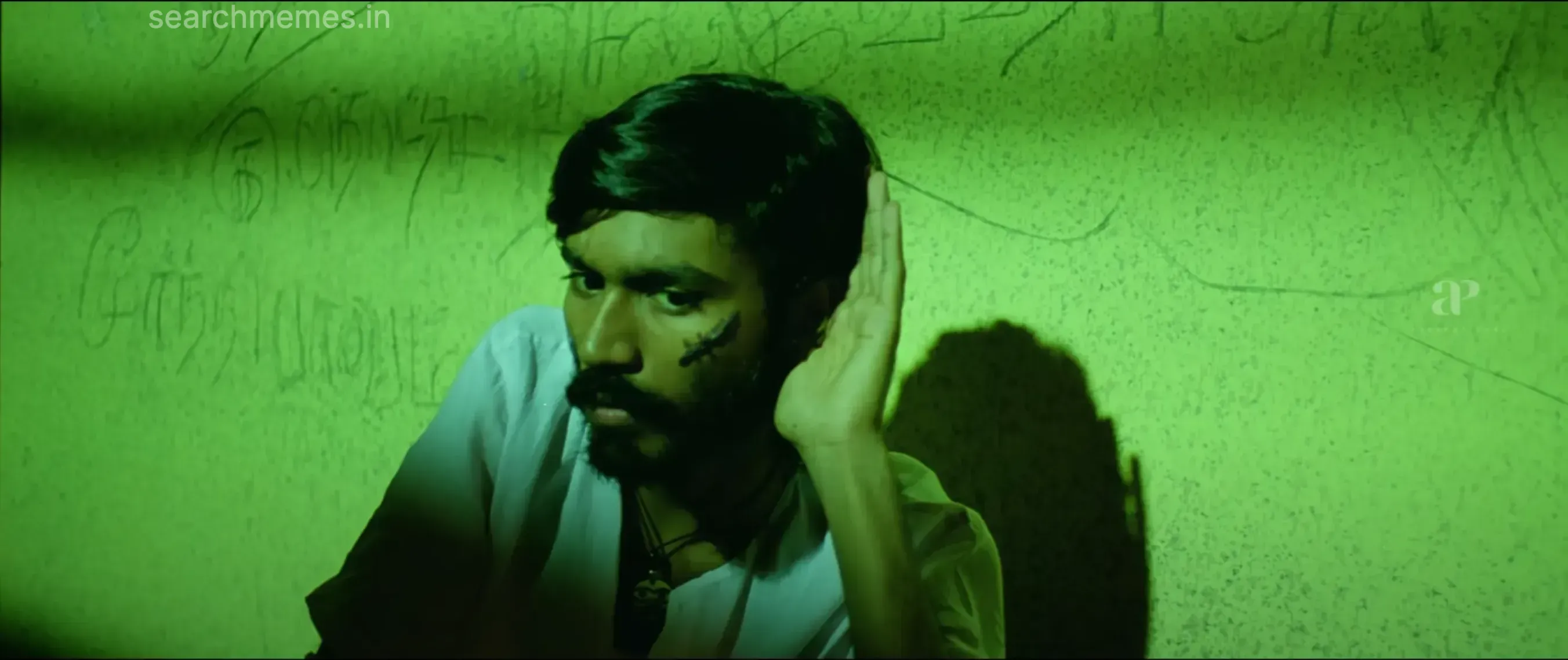 Dhanush sitting in darkness listening cautiously with fearful tired eyes