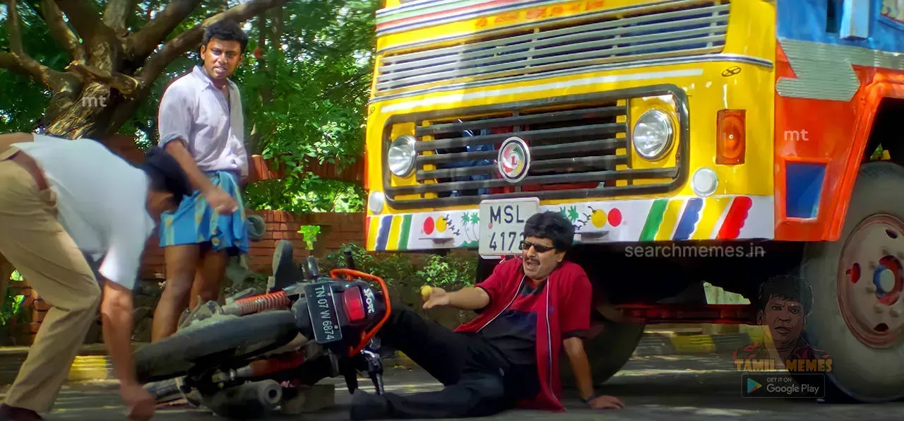 Vivek fallen on the road in front of a large lorry beside his overturned bike