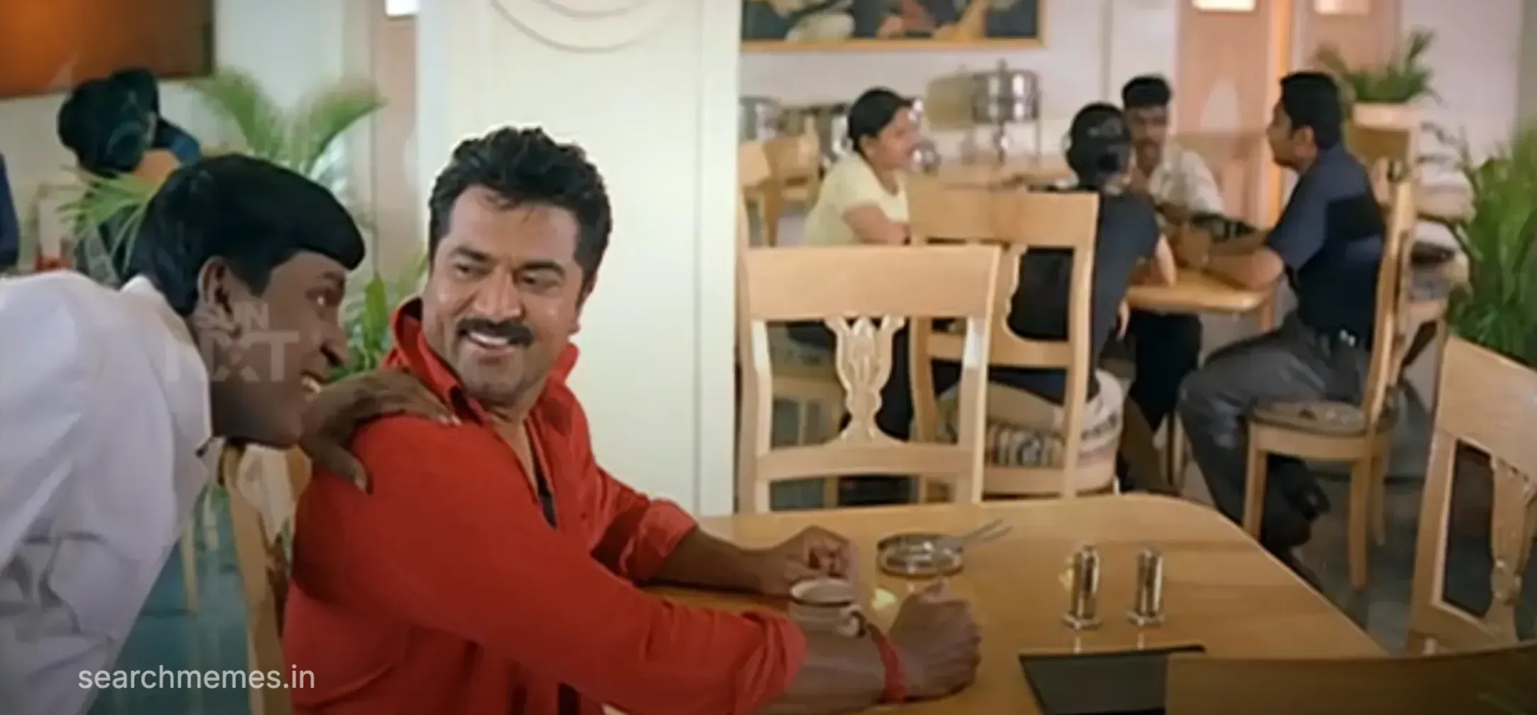 Vadivelu resting his hand on Sarathkumar's shoulder while chatting at a dining table