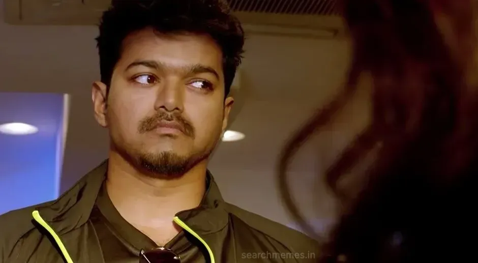 Vijay giving an uneasy side-eye glance in a dark track jacket in Thuppakki