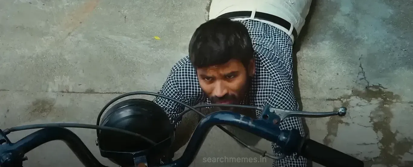 Dhanush leaning over his old moped gently talking with affection and regret