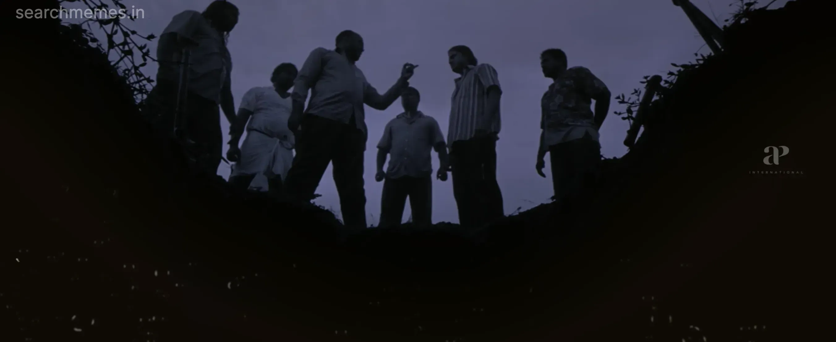 Silhouettes of several men standing around the rim of a deep dark trench