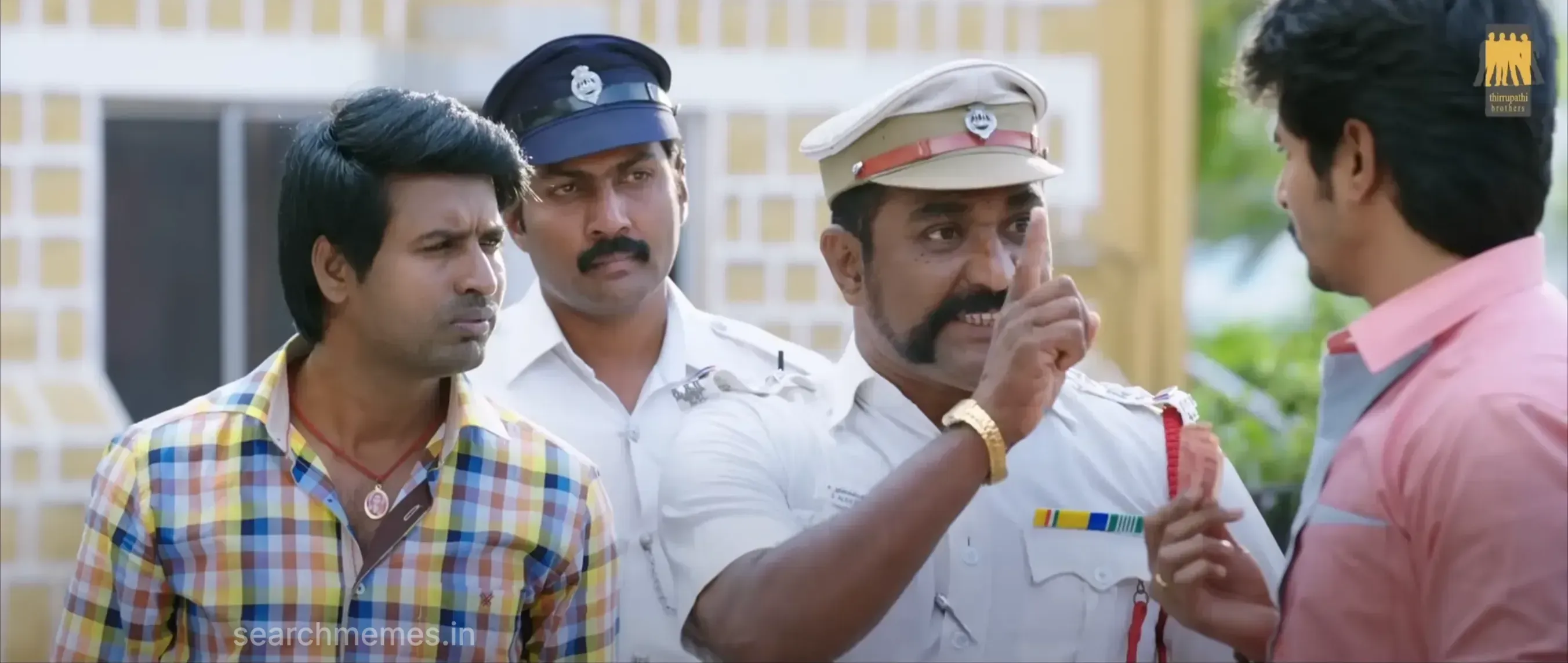 A police officer pointing an index finger sternly while Sivakarthikeyan listens