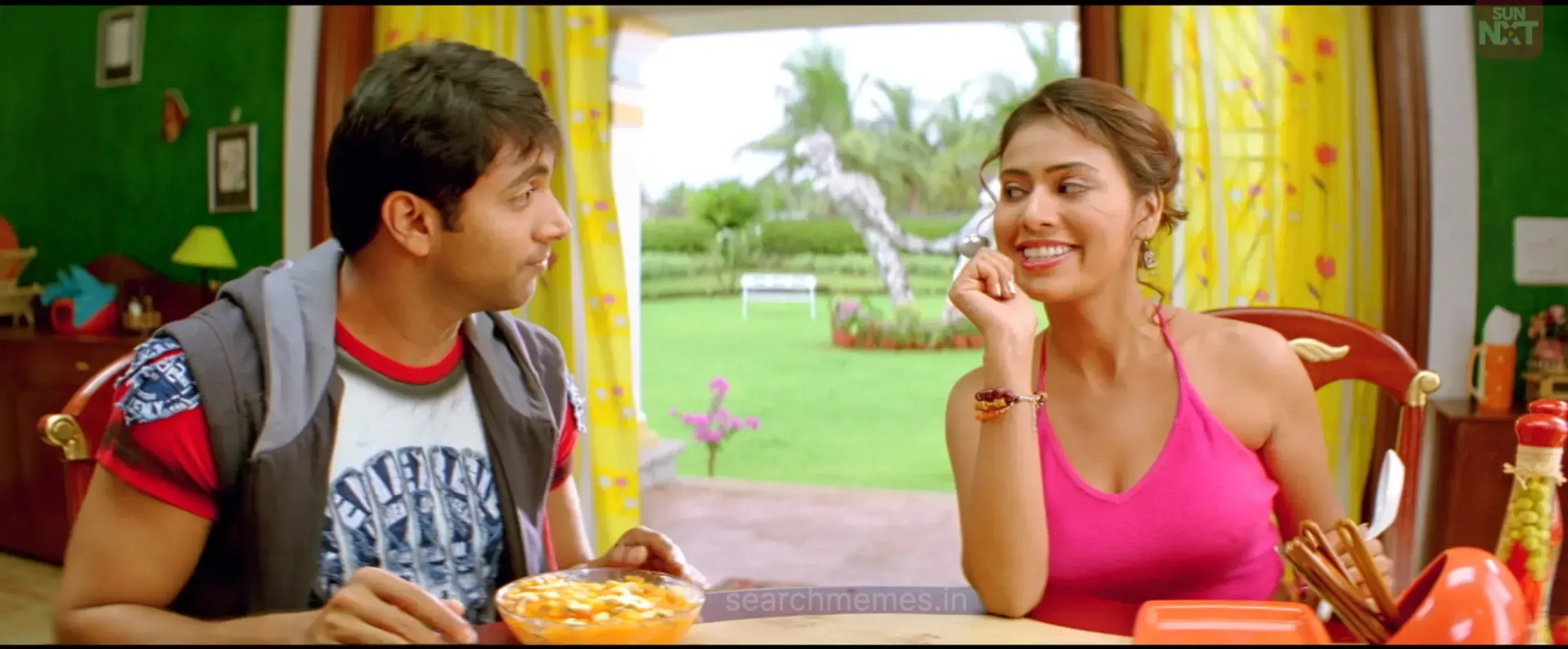 Jayam Ravi sitting at a dining table looking at a smiling Trisha in a pink top