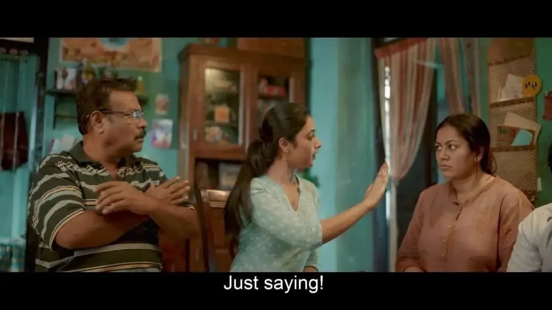 Priyanka Mohan gesturing with raised hand at a family dining table with subtitle Just saying