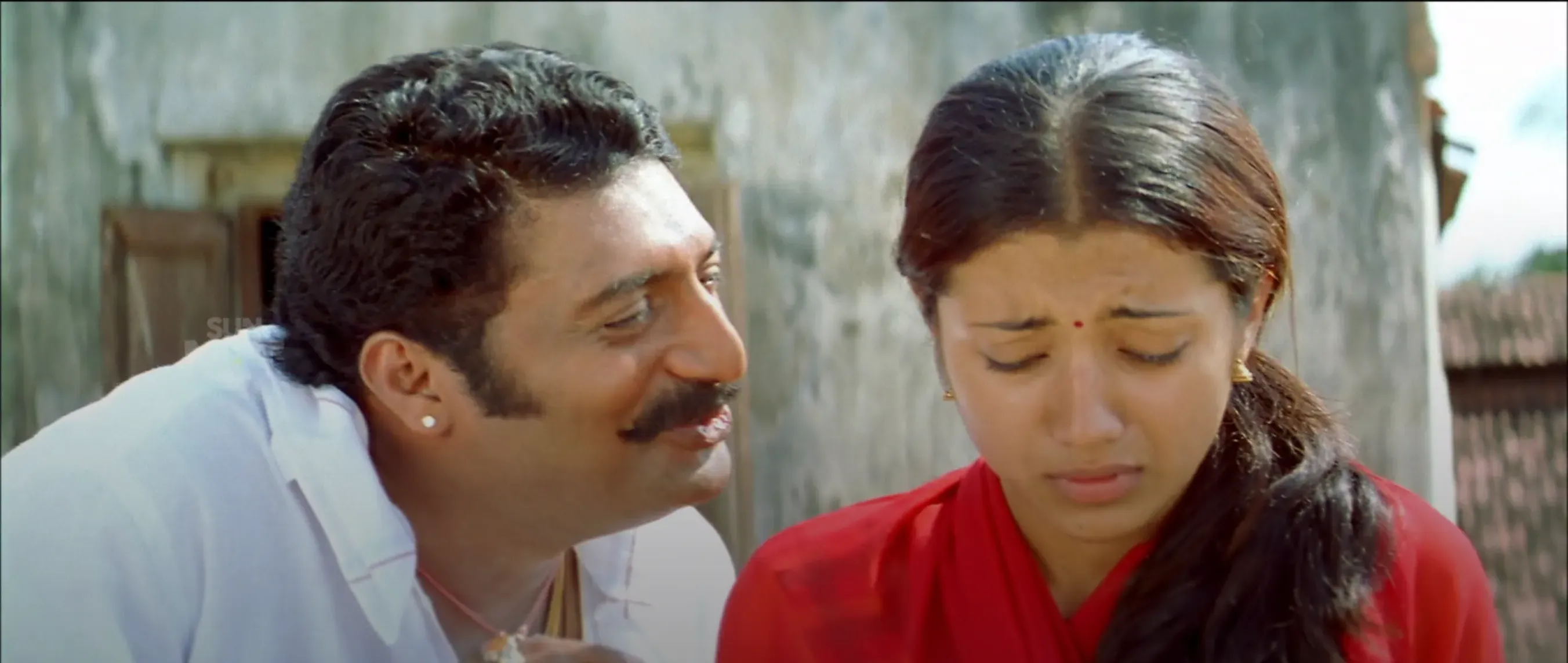 Prakash Raj leaning close with an obsessive smile next to a fearful Trisha