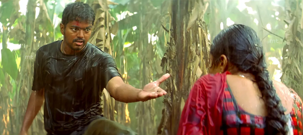 Rain-soaked Vijay extending his open hand forward while facing Trisha in a grove