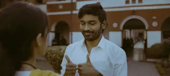 Dhanush showing two thumbs up with a bittersweet forced smile in a white shirt