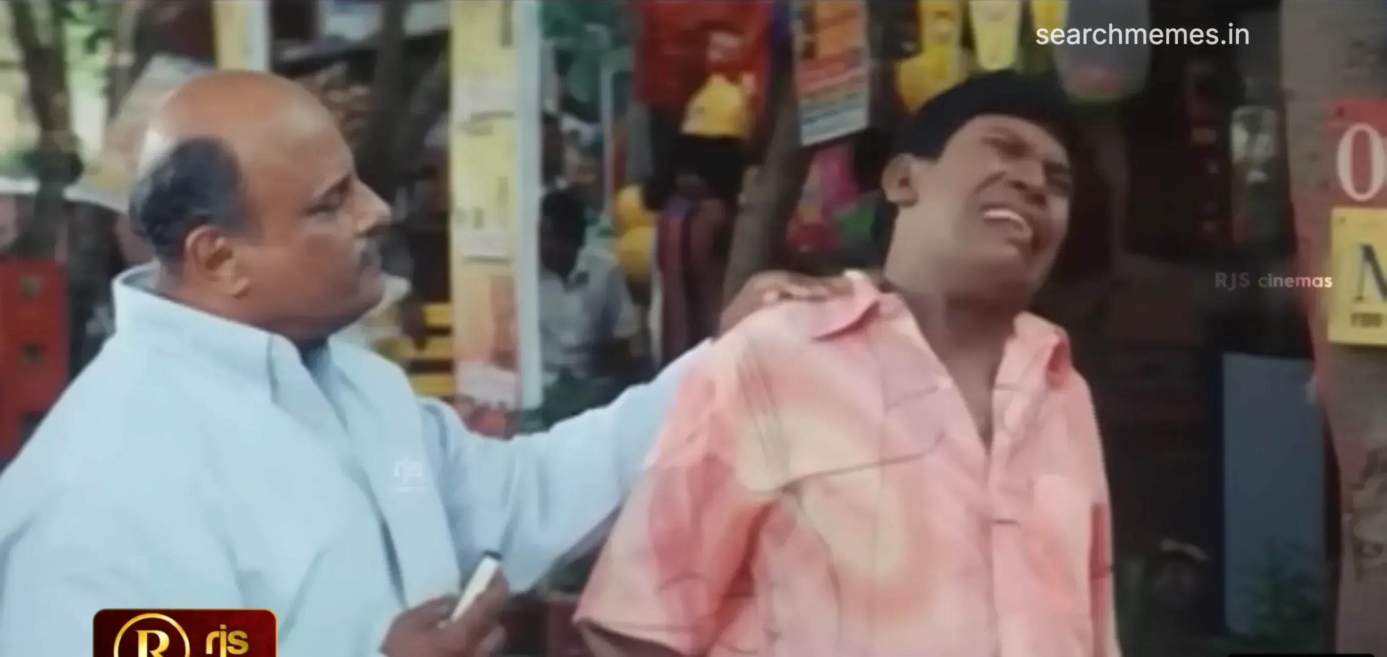Vadivelu making a painful crying expression as a man grips his shoulder