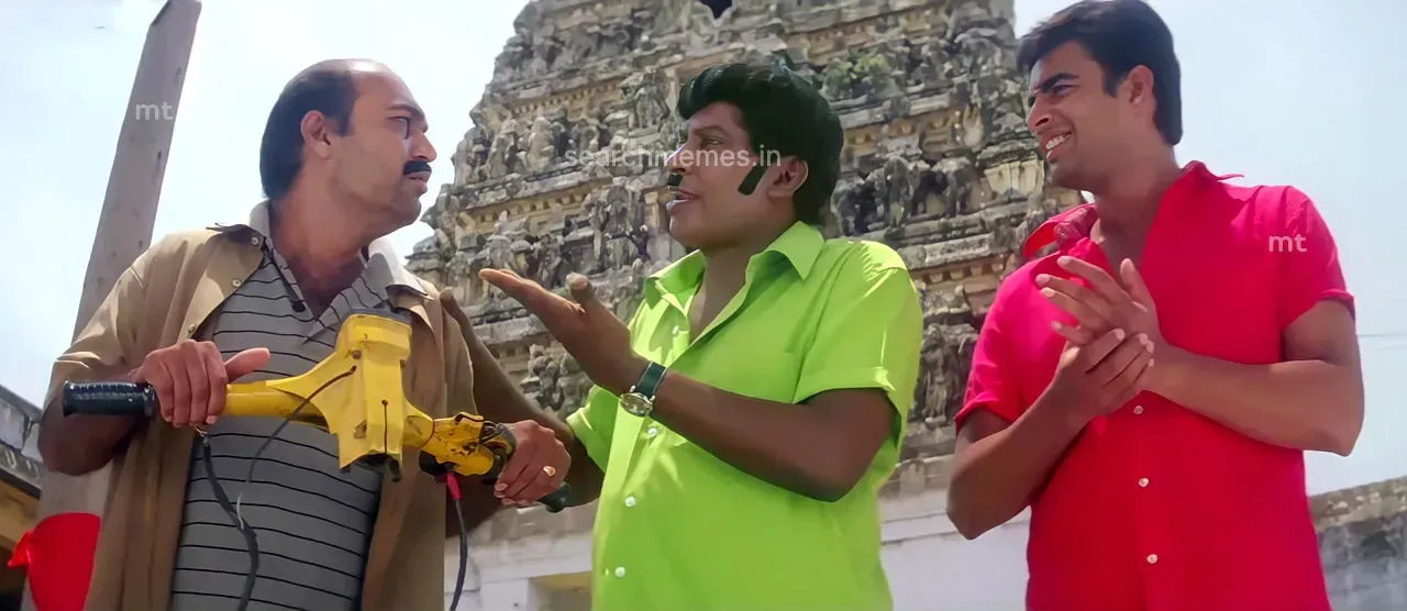 Vadivelu talking animatedly next to Madhavan while another man holds a broken vehicle handle