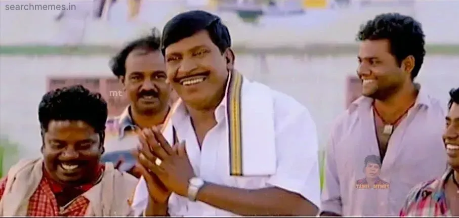 Vadivelu from Ayya smiling and doing a 'Vanakkam' gesture, surrounded by smiling men.