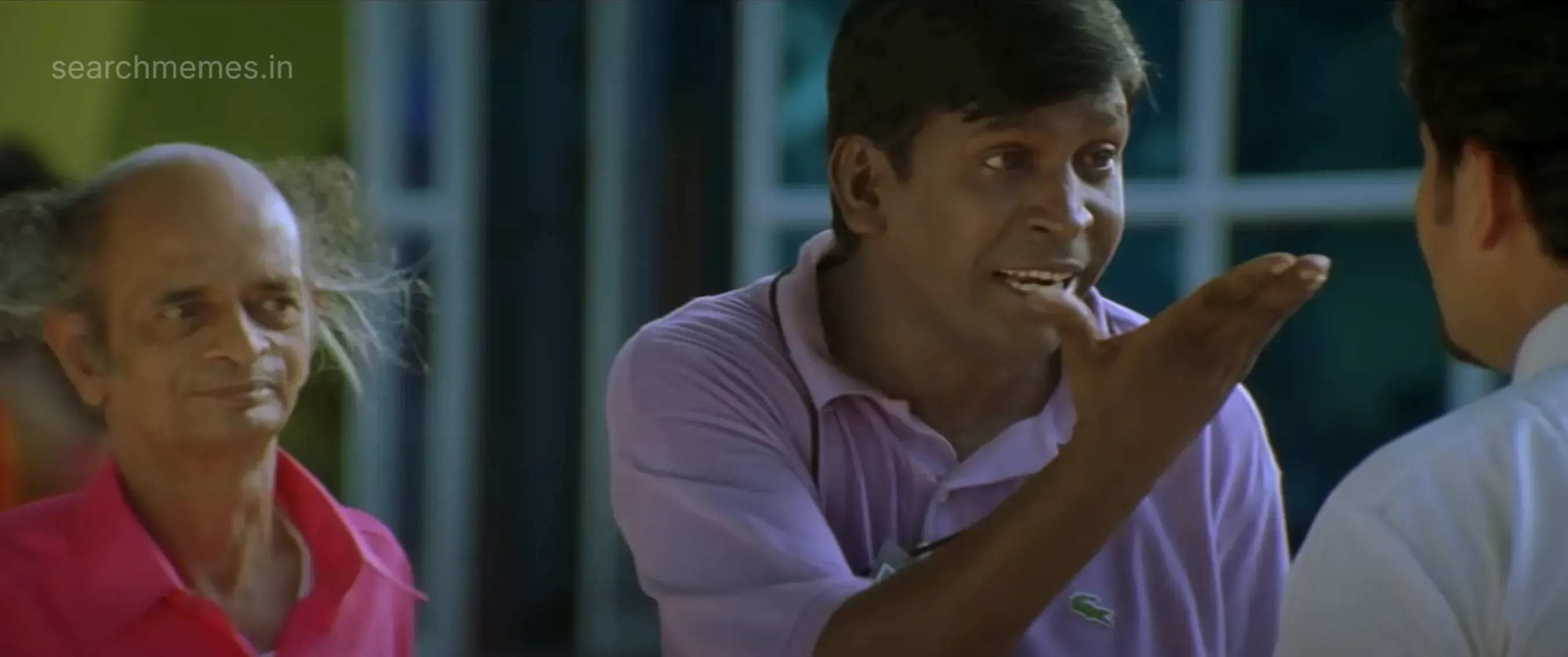 Vadivelu angrily pointing his finger at someone, while Omakkuchi Narasimhan watches