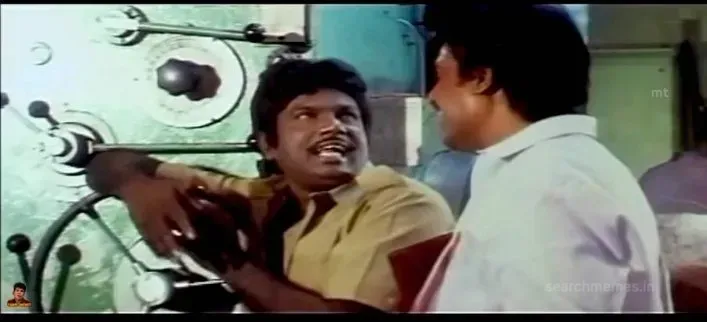 Koundamani leaning on industrial machinery talking to another worker