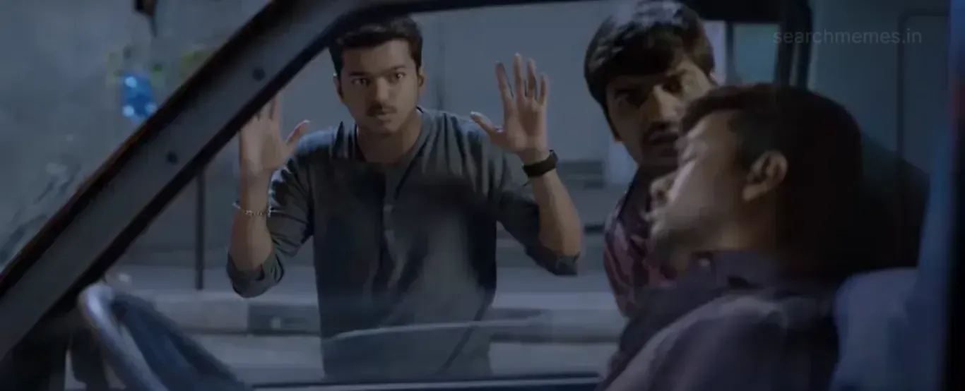 Vijay staring in shock with hands raised against a vehicle window alongside Sathish