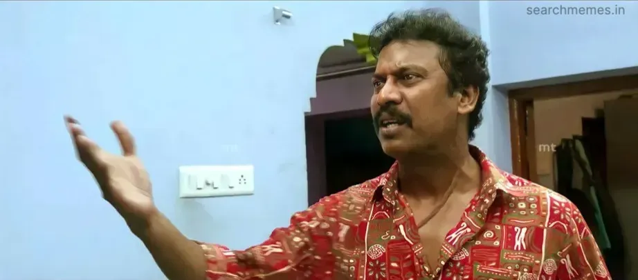 Samuthirakani with a frustrated and questioning expression, raising his hand in Vada Chennai.