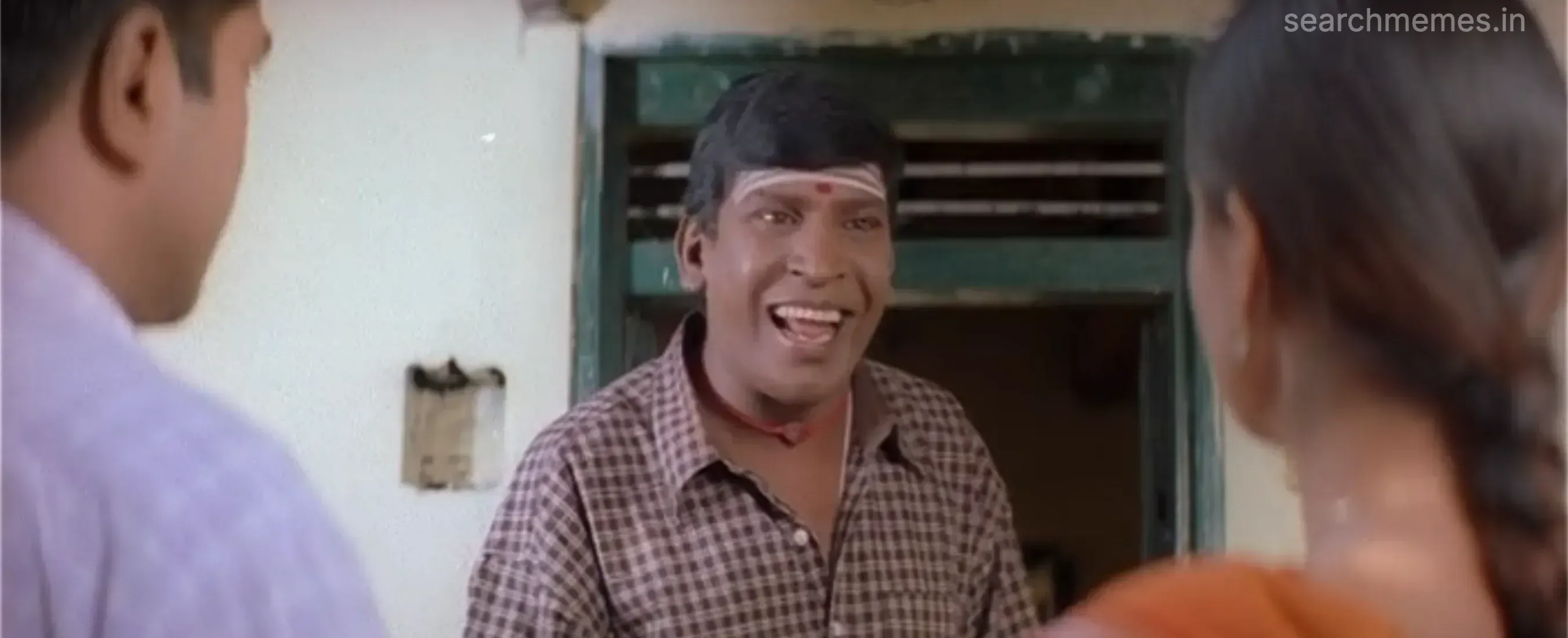 Vadivelu grinning widely at the doorway during a conversation