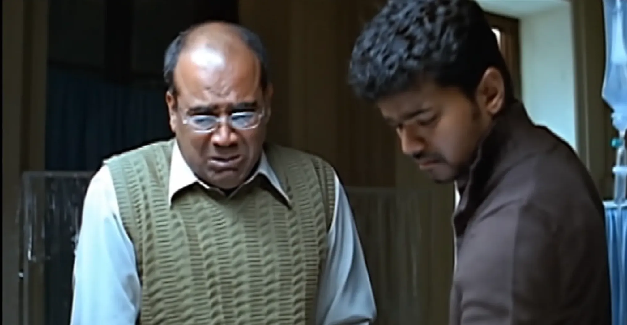 Vijay talking gently to an emotional older man wearing glasses in Sachein