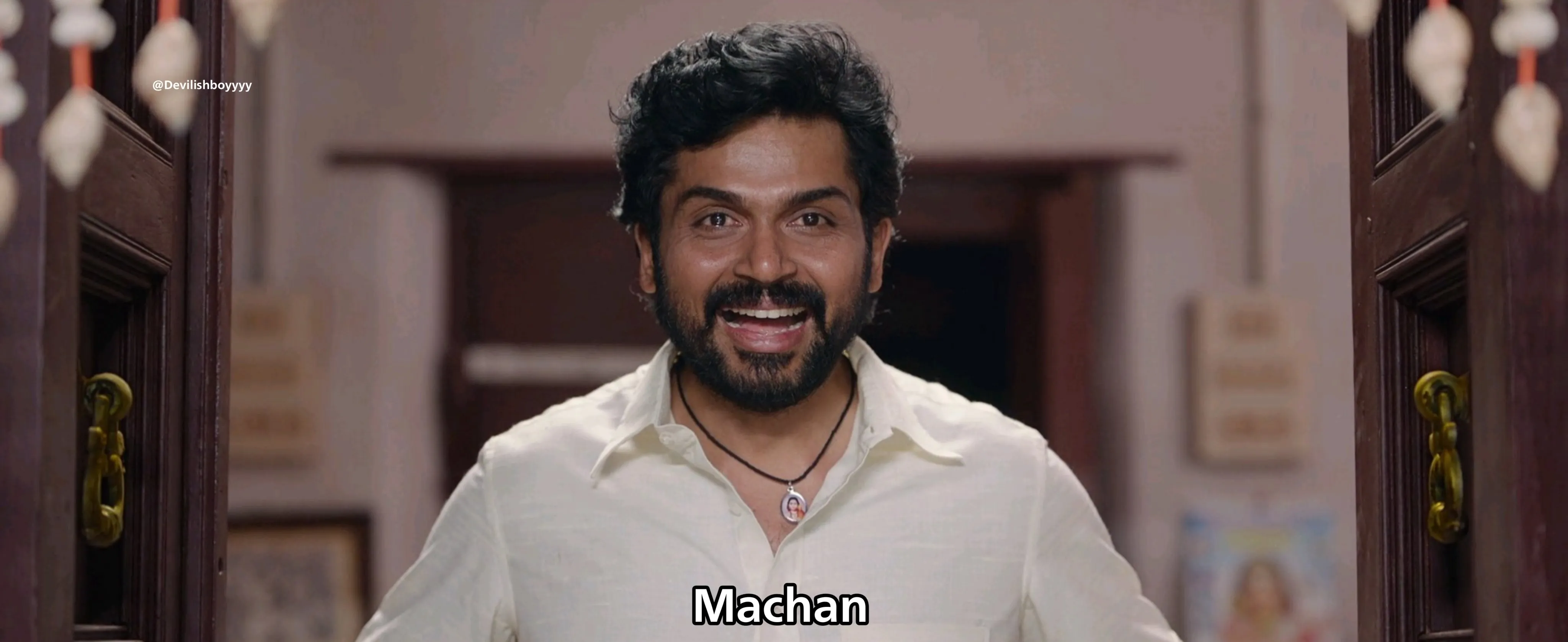 Karthi smiling broadly in a white shirt at a doorway