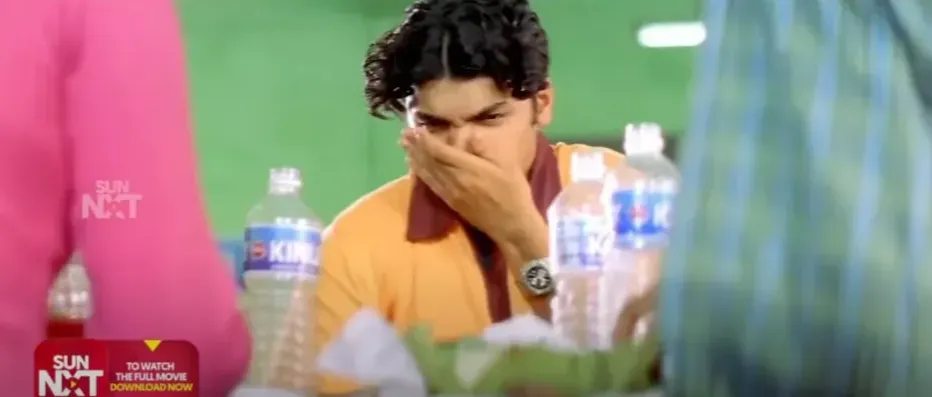 Dhanush covering his face in disgust at a dining table