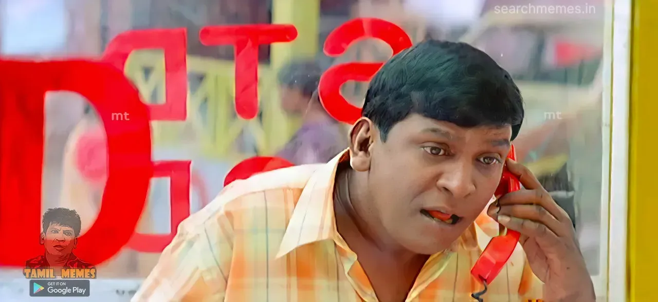 Vadivelu listening puzzled through a red handset behind STD glass booth