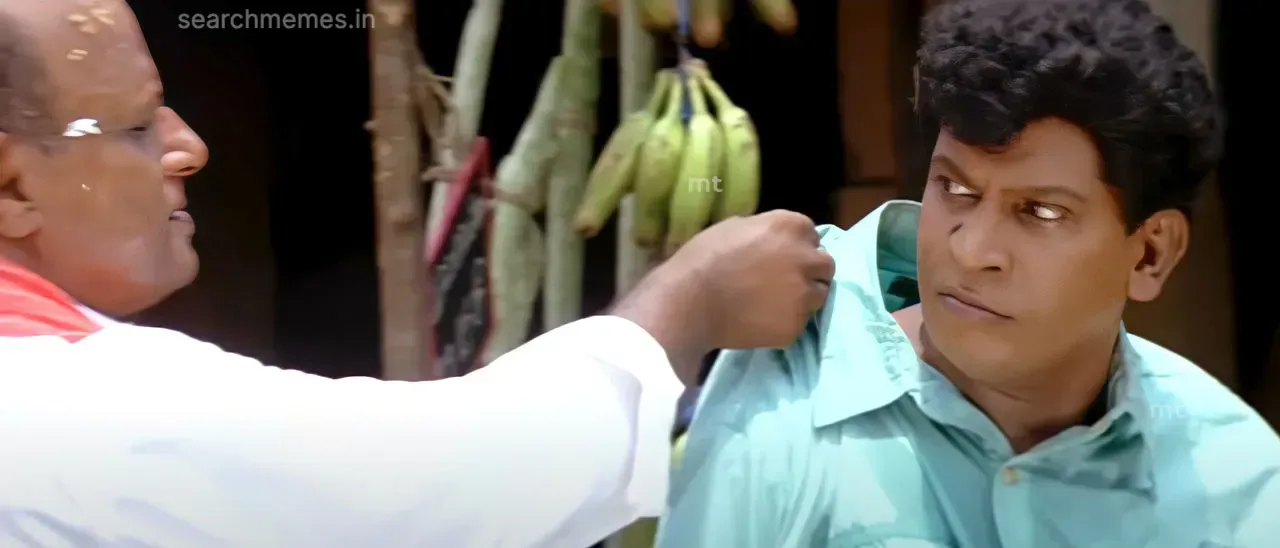 Vadivelu turning back with an angry intense stare while someone holds his shirt collar