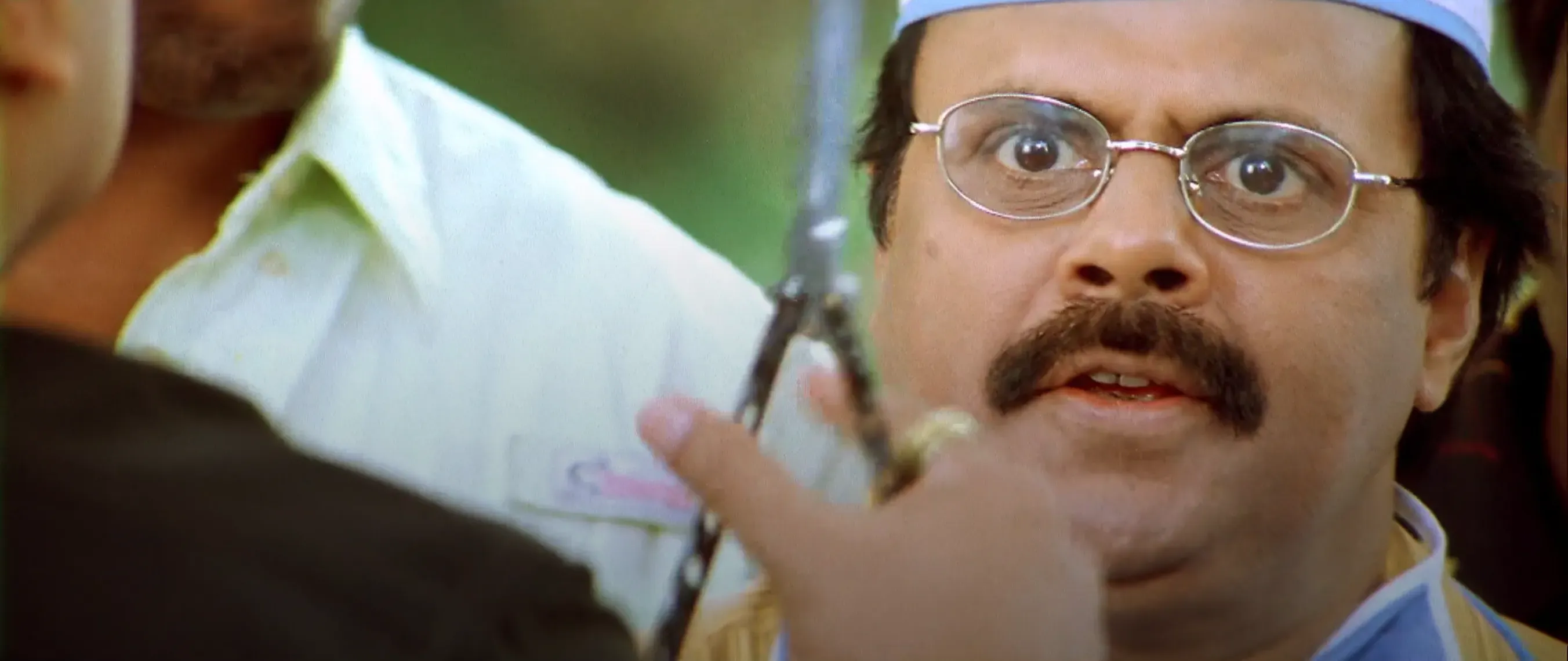 Kamal Haasan leaning close to Crazy Mohan with an intimidating funny glare