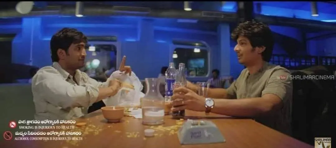Santhanam and Jiiva seated with drinks pointing out a mistake casually